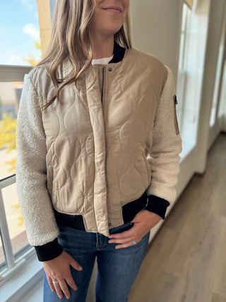 Person wearing a beige quilted jacket indoors