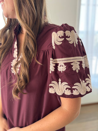 Maroon blouse with white embroidery on a blurred background