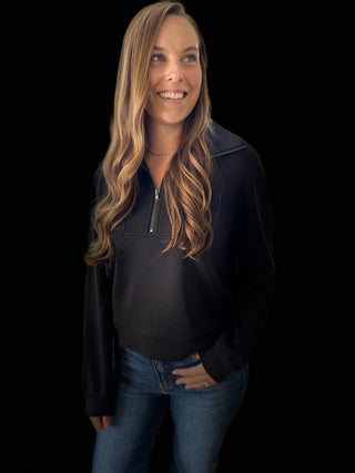 Woman wearing a black jacket and blue jeans against a black background