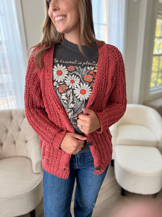 Woman wearing a red cardigan over a floral t-shirt in a living room.