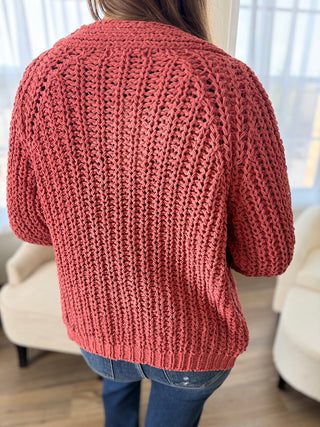 Person wearing a chunky knit pink sweater in a living room setting