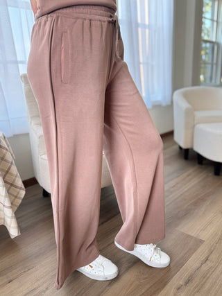 Person wearing pink pants and white sneakers in a room with light-colored furniture.
