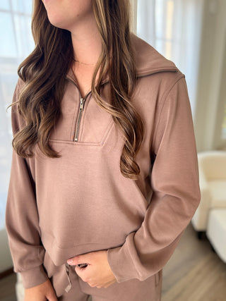Person standing wearing a brown half zip top.