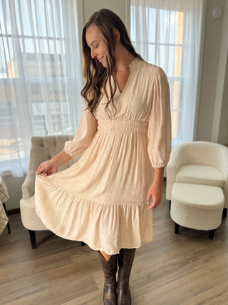 Woman wearing a beige dress in a living room setting