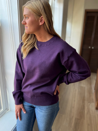 Photo of a woman in a plum sweater.