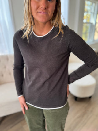 Person wearing a dark gray long-sleeve shirt and green pants indoors.