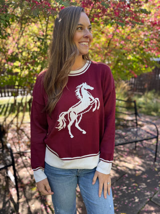 Woman in a burgundy knit sweater with cream rearing horse graphic | V-Rae's Boutique