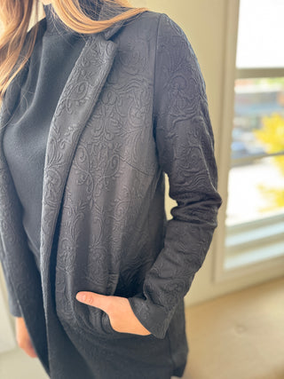 Dark gray textured jacket worn by a person indoors.