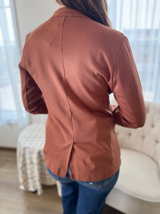 Person wearing a brown jacket in a room with a couch and lamp.