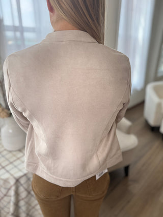 Person wearing a beige jacket indoors with a blurred background