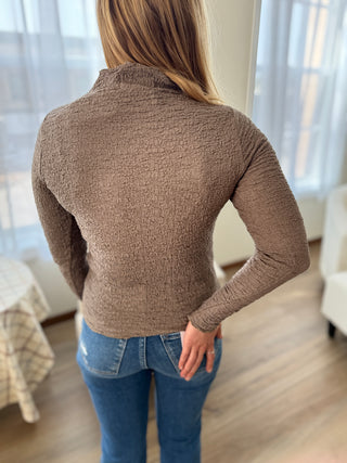 Photo of a woman wearing a fitted brown top.