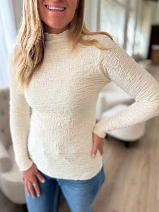 Photo of a woman wearing a fitted cream top.