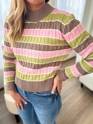Person wearing a multicolored striped sweater and jeans indoors.
