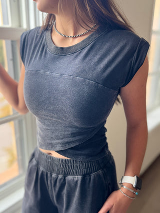 Person wearing a blue athletic outfit standing by a window.