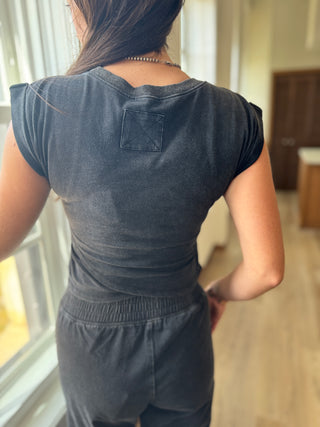 Person wearing a dark gray outfit in a room with a window.