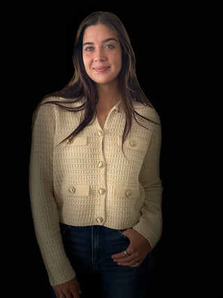 Woman wearing a beige textured cardigan against a black background