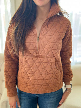 Person wearing a brown quilted pullover with a neutral background