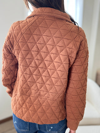 Person wearing a brown quilted jacket indoors
