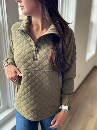 Person wearing a green quilted jacket indoors