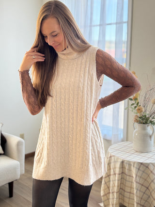 Woman wearing a cream-colored sleeveless sweater in a home setting