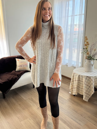 Woman wearing a long-sleeve dress with lace sleeves in a living room.