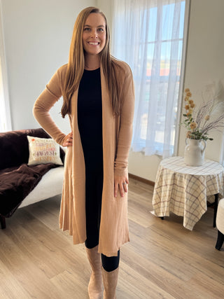 Woman wearing a beige cardigan in a living room setting