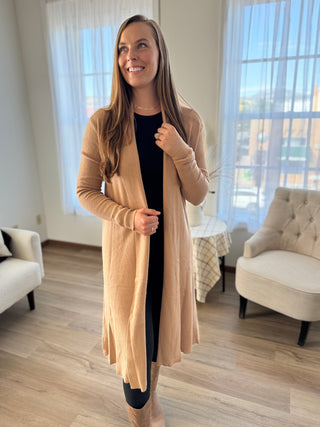 Woman wearing a beige cardigan in a living room setting