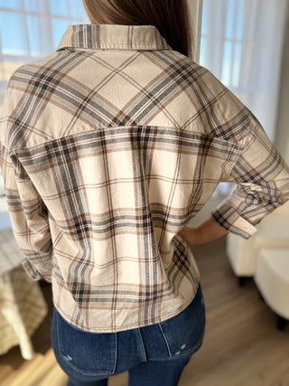 Person wearing a plaid shirt with a neutral color palette indoors.