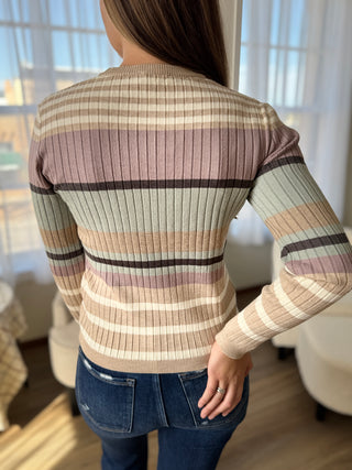 Person wearing a striped sweater with a blurred indoor background