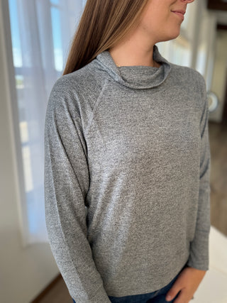 Person wearing a gray long-sleeve shirt indoors