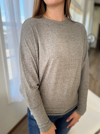 Person wearing a gray long-sleeve shirt in a home setting