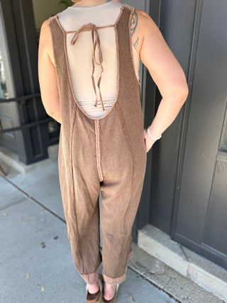 Person wearing a brown overalls with a plain background
