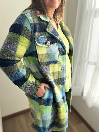Person wearing a green and blue plaid coat indoors.