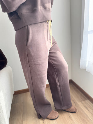 Person wearing gray sweatpants standing indoors with a light background