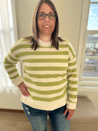 Woman wearing a green and white striped sweater indoors.