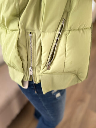 Light green puffer jacket with zippers on a neutral background