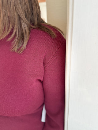 Person wearing a pink sweater with a blurred background
