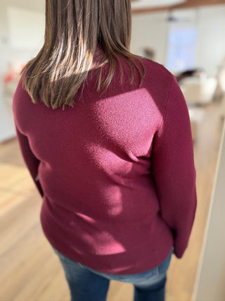 Person wearing a maroon sweater in an indoor setting