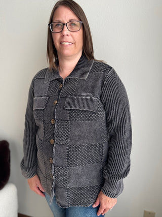 Woman wearing a gray textured sweater against a plain background