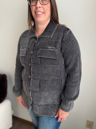 Woman wearing a textured gray jacket with a plain background