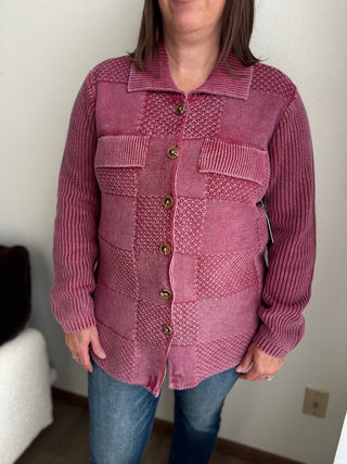 Person wearing a pink textured shirt with buttons against a plain background