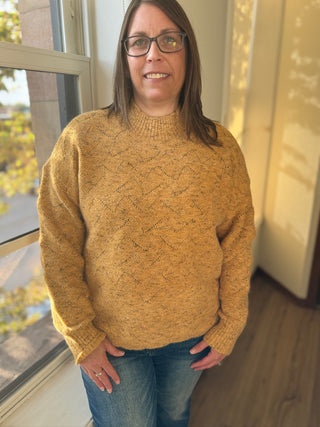 Person wearing a mustard yellow sweater standing by a window
