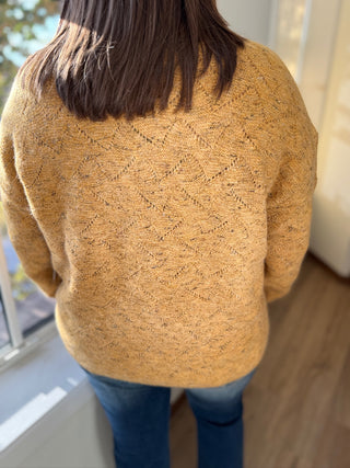 Person wearing a mustard yellow sweater with a blurred background