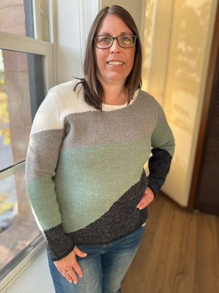 Woman wearing a striped sweater standing indoors near a window.