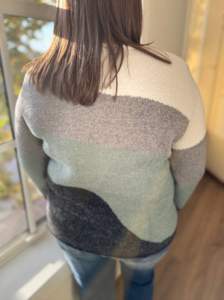 Person wearing a multicolored sweater with a neutral background