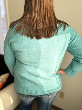 Person wearing a light blue sweater in an indoor setting