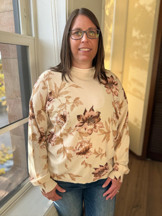 Woman wearing a floral sweater standing by a window