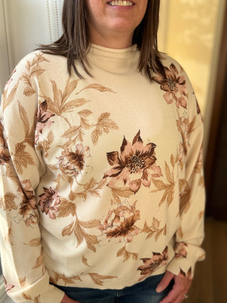 Person wearing a beige sweater with floral patterns indoors