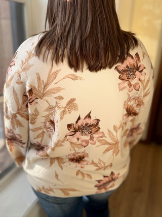 Person wearing a floral-patterned sweater with a neutral background