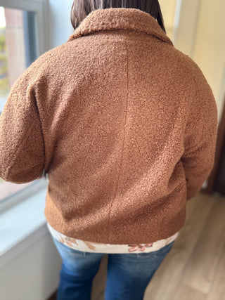 Person wearing a brown fleece jacket indoors near a window